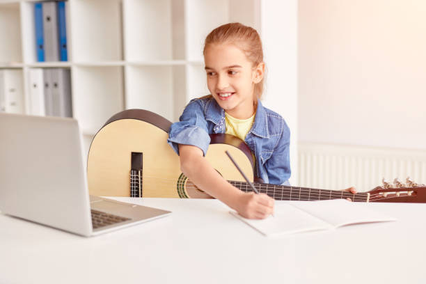 istock Cheerful child making notes during online guitar lesson 1191142958