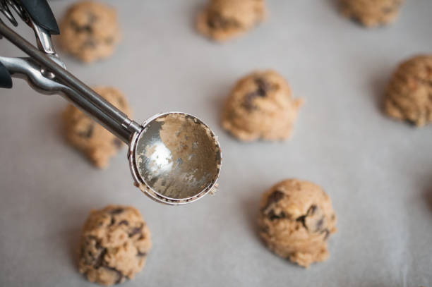 Freshly prepared chocolate chip cookies bake in a cozy home kitchen oven. The golden dough captures the essence of homemade delight, promising a delicious treat.