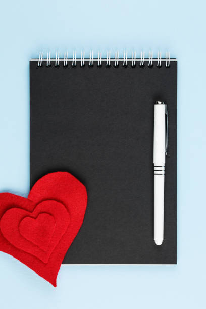 istock red heart on black notebook on blue background 1191152029