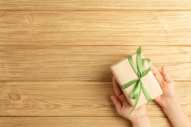 istock gift box in the hands on a wooden background 1191152934