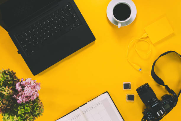 istock Conceptual workspace, Laptop computer and coffee cup, note book with Camera and flower vase. External hard disk with USB on pastel background yellow. Top view. Flat lay. summer 1191154735