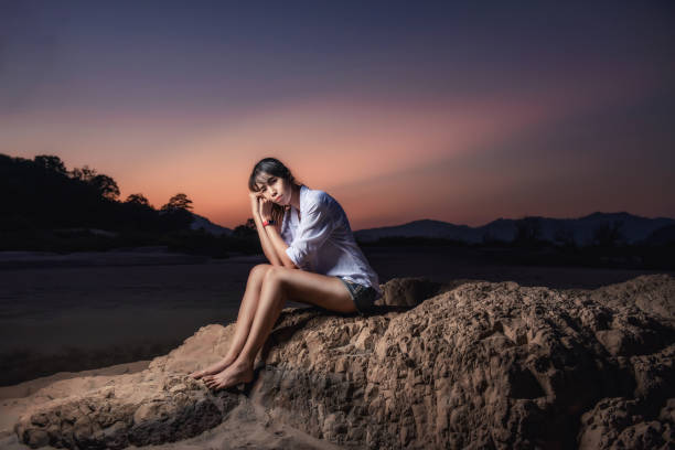 Woman traveler sitting on a rock in sea shore of the Thailand beach stock photo