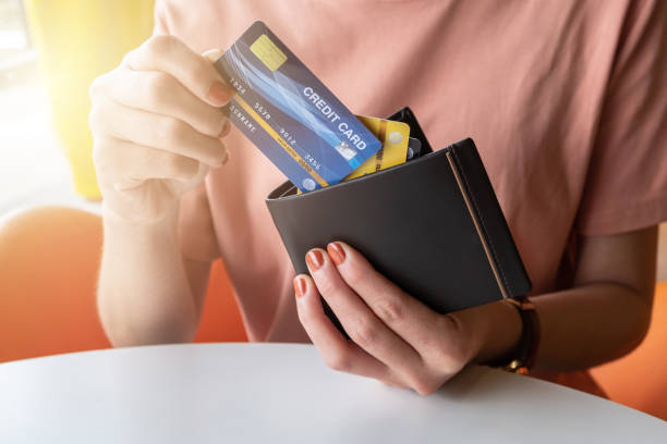 vista recortada de manos femeninas recogiendo tarjetas de crédito de su billetera. - credit cards fotografías e imágenes de stock