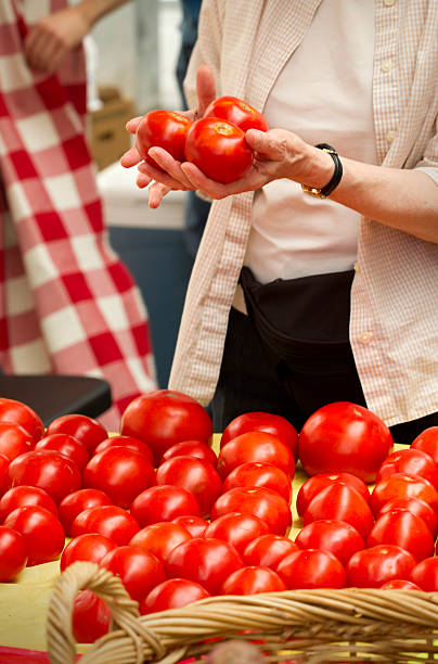 Mulher compra de Tomates maduros frescos em farmer's market - foto de acervo