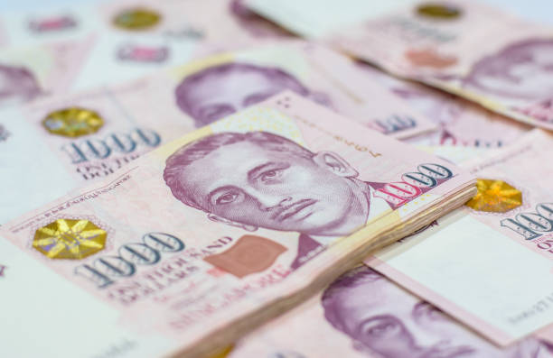 Background of Singapore dollar currency.Focus on eye of a man on banknotes Background of Singapore dollar currency.Focus on eye of a man on banknotes singapore cash stock pictures, royalty-free photos & images