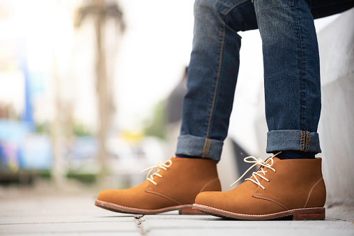 Fashion model wearing blue jeans and brown ankle boots.