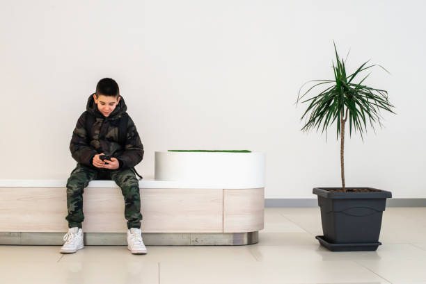 teenager playing with smartphone in modern commercial center. technology and communication concept with child in contemporary building interior. - 16707 imagens e fotografias de stock