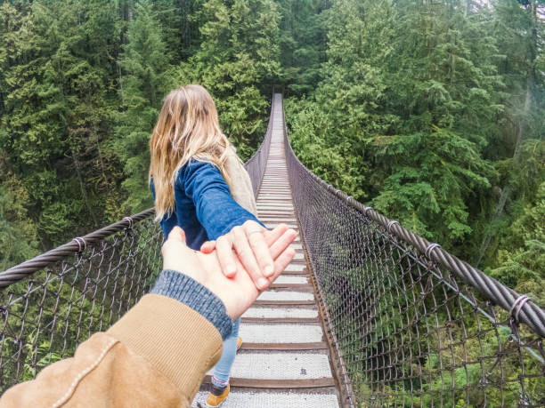siga-me ao conceito, jovem mulher levando namorado para a floresta na ponte suspensa - vancouver suspension bridge bridge people - fotografias e filmes do acervo