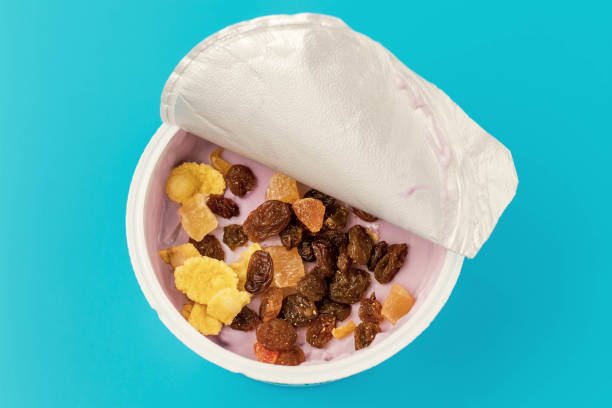 Pink yogurt in a jar with cereal and raisins on a turquoise background. Fruit yogurt in a open container on a blue backdrop. Top view. stock photo
