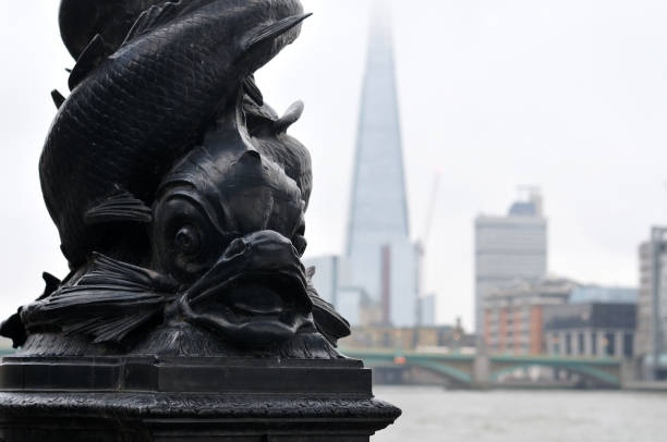 detail of a cast iron lamp post with fantasy fish cast iron lamp post with fish ornament at embankment of river thames in London with the shard in blurry background the shard close up stock pictures, royalty-free photos & images
