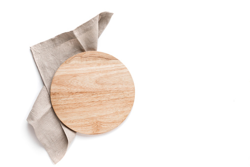 Empty wooden platter with linen napkin isolated on white background, top view, copy space. Wooden cutting board for pizza, design element.
