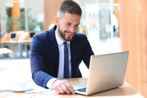 istock Smiling man sitting in office and using his laptop. 1191186706