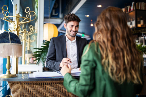 hotel receptionist helpt gasten om in te checken - hotel stockfoto's en -beelden