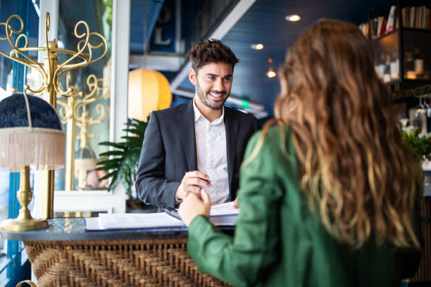 Hotel receptionist assisting guest for checking in Male hotel receptionist helping a woman guest in checking in process. Woman in hotel check-in at reception talking with the concierge at front office. luxury hotel photos stock pictures, royalty-free photos & images