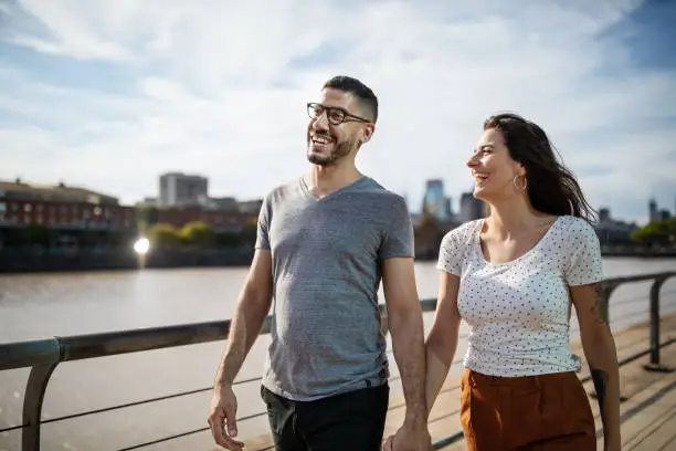 Photo of Happy young couple walking together on city boardwalk