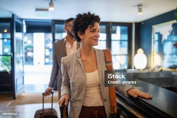 Business Travelers Arriving At Hotel Reception Desk Stock Photo - Download Image Now