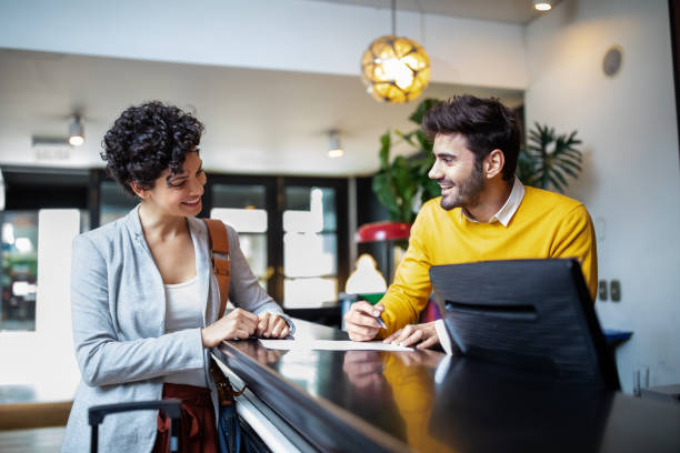 Tourist registering in hotel Young businesswoman arriving at the hotel and filling in registration documents at reception desk. receptionist stock pictures, royalty-free photos & images