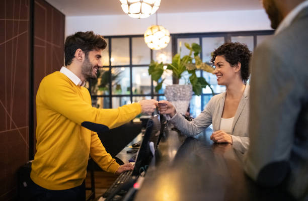 business woman getting key card from hotel reception - hotel reception imagens e fotografias de stock