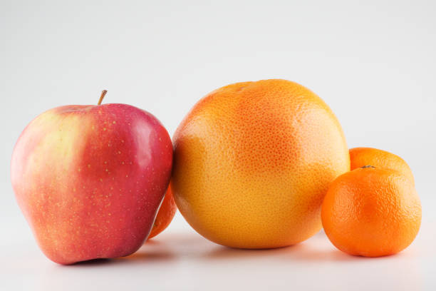 manzanas y naranja aisladas sobre un fondo blanco - individuality standing out from the crowd apple contrasts fotografías e imágenes de stock