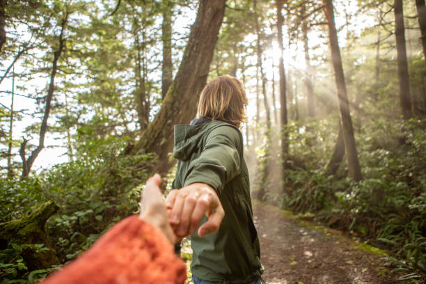 istock Follow me to concept, young man leading girlfriend to forest path; sunlight 1191200347