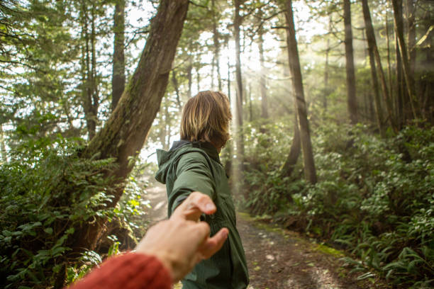 istock Follow me to concept, young man leading girlfriend to forest path; sunlight 1191201003