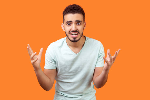 how could you? portrait of annoyed frustrated brunette man standing with raised hands, asking why. indoor studio shot isolated on orange background - rudeness manager emotional stress asian ethnicity imagens e fotografias de stock