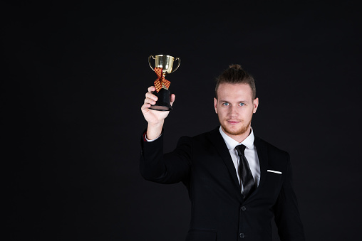 Confident businessman in black suit with Trophy
