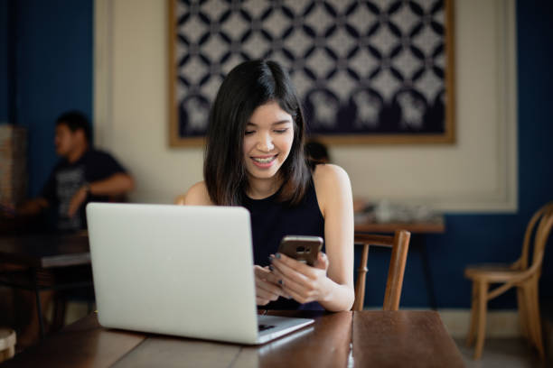 istock Asian girl freelance using smartphone while working with her laptop in coffeeshop. 1191203727