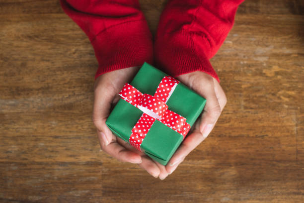 istock Female hands holding a small gift in selective focus. 1191203753