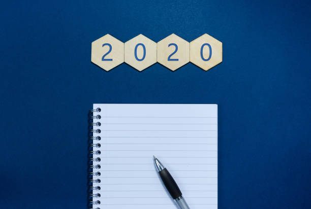 istock 2020 written on wooden hexagons  with notepad and pen. 1191203860
