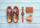 Brown nubuck leather set with wallet and belt accessory for men isolated on blue wooden background. Top view.