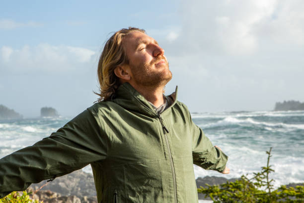 istock Young man standing on coastline arms outstretched, wilderness area 1191206036