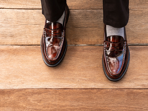 The men fashion model wearing the brown shoes leather on wooden floor.