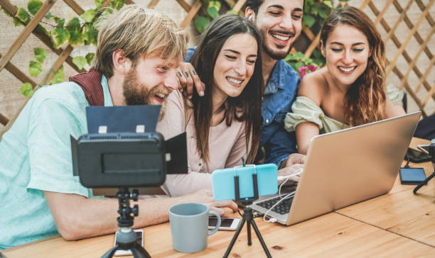 istock Young people streaming online using laptop, smartphone camera and softbox light - Millennial friends having fun with new technology trend - Social media, vlogging concept - Soft focus on left man face 1191207363