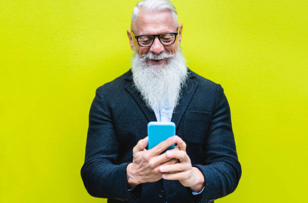 istock Happy senior man using smartphone app with fluorescent color in background - Hipster old guy having fun with technology - Tech and joyful elderly concept - Focus on his face 1191208790