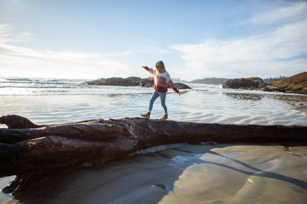 istock Young woman walking on tree trunk on beach balancing body weight 1191217890