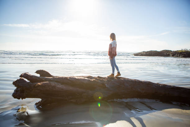 istock Young woman walking on tree trunk on beach balancing body weight 1191219076