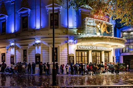 This is a West End theatre in the City of Westminster, located in Northumberland Avenue. It is taken at night with queues forming for the play 'Cyrano de Bergerac'
