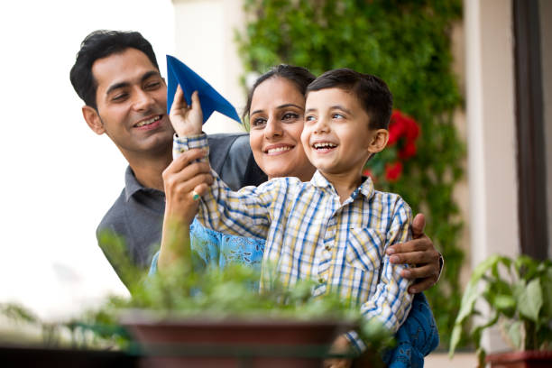 紙飛行機で遊ぶインドの家族 - offspring family love india ストックフォトと画像
