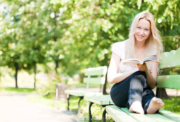 istock young woman reading book in park 119122883