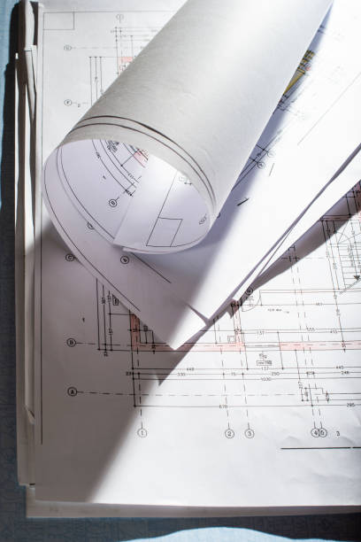 istock Blueprints on architect desk. Stacked and rolled up architectural projects on natural window light. 1191230599
