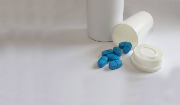 istock white bottle with caps and blue pills for diseased treatment, white background. 1191231741