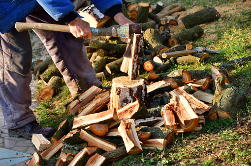 Splitting wood with an ax into smaller logs in traditional way