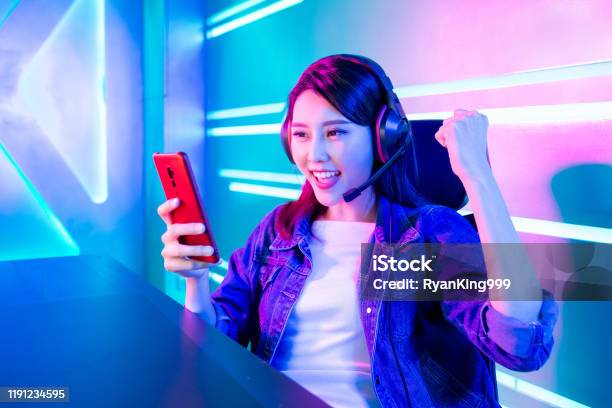 Happy asia girl gamer wear headphone competition play video game online  with smartphone colorful neon lights in living room at home. Esport  streaming game online, Home quarantine activity concept. 3652236 Stock Photo