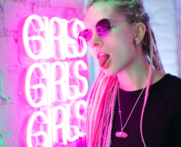 menina em luzes de néon no nightclub, mulher bonita, com cabelo cor-de-rosa longo, com pigtails dos dreadlocks, anos 80 à moda brilhantes, meninas da palavra de néon na parede - dramatic make up - fotografias e filmes do acervo