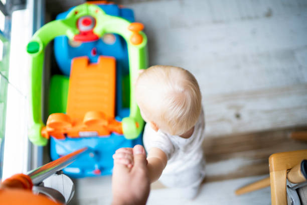istock Parent supporting baby boy on his first steps 1191236646