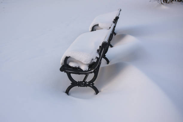 snow drifted on and around a park bench. - drifted imagens e fotografias de stock