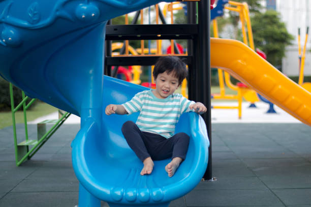 istock Young boy playing on a blue playground slide 1191242602