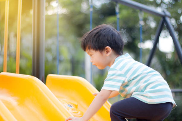 istock Young boy playing on a yellow playground slide 1191242605