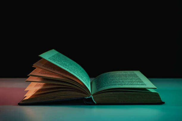 istock Beautiful open book in the color light on a table and night background. 1191243779